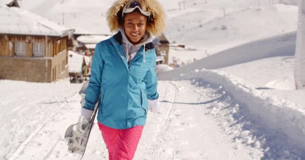 Smiling young woman carrying snowboard — Stock Video