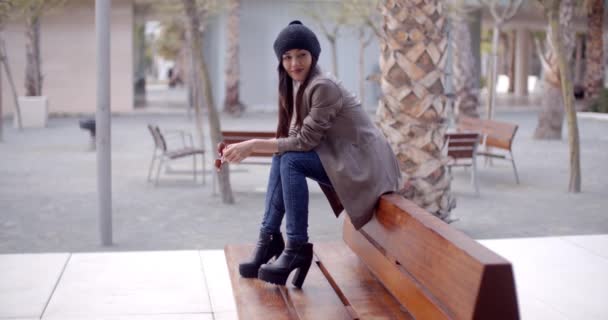 Женщина сидит и ждет на скамейке — стоковое видео