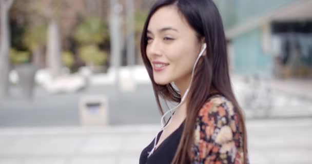 Женщина ходит, слушая музыку в наушниках — стоковое видео