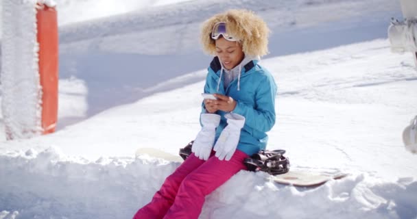 Mujer sentada en el banco de nieve y mensajes de texto — Vídeos de Stock