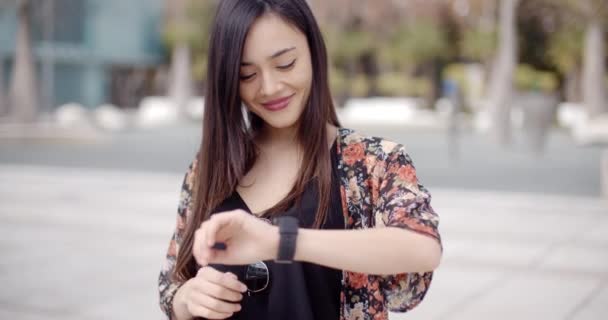 Frau schaut lächelnd auf Armbanduhr — Stockvideo