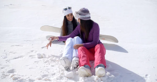Women sitting waiting in snow with snowboard — 图库照片