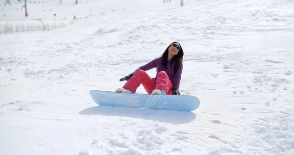 Kobieta siedzi w śniegu za pomocą snowboardowe — Zdjęcie stockowe