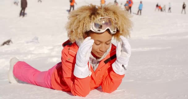 Mujer con gafas de sol y acostada en la nieve — Vídeos de Stock