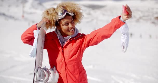 Woman carrying snowboard and taking selfie — Wideo stockowe