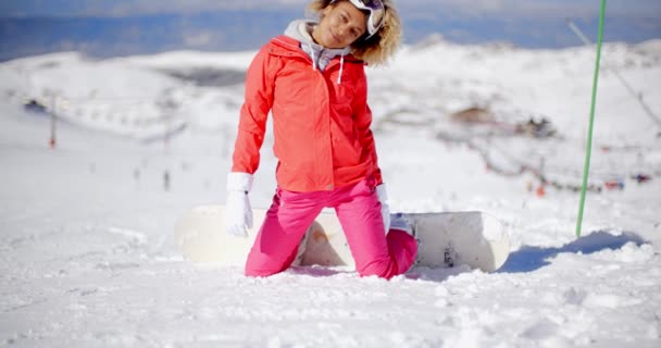 Frau sitzt mit Snowboard im Schnee — Stockvideo