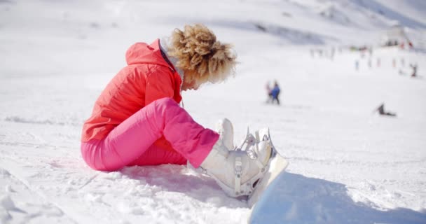 Γυναίκα που κάθεται στο χιόνι χρησιμοποιώντας snowboard — Αρχείο Βίντεο