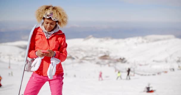 Женщина, несущая сноуборд и печатающая на мобильном — стоковое видео