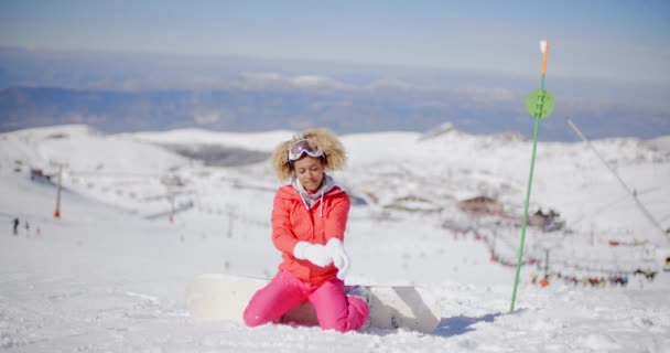 Kvinna sitter i snö med snowboard — Stockvideo