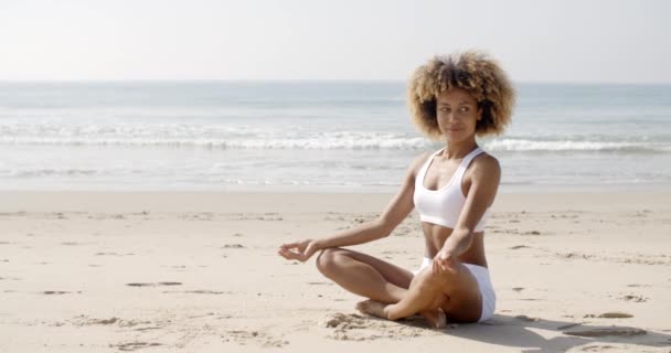 Жінка сидить у позі йоги на пляжі — стокове відео
