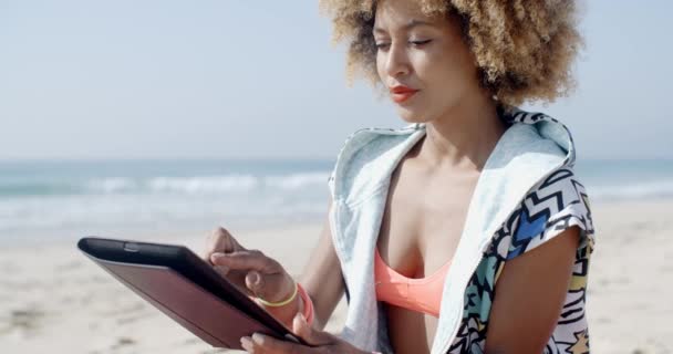 Женщина с помощью тачпада планшета на пляже — стоковое видео