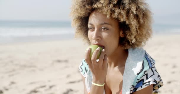 Woman eten apple op strand — Stockvideo