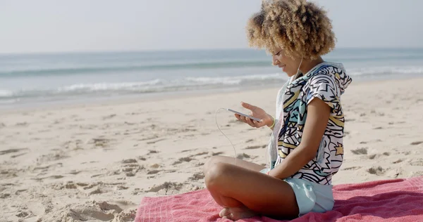 Mujer escuchando música en auriculares en la playa — Foto de Stock