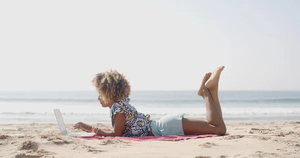 Frau tippt am Strand auf Laptop — Stockfoto