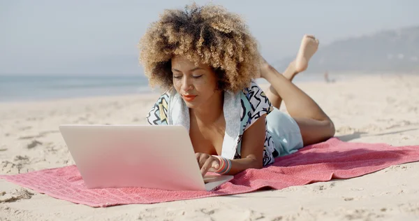 Девушка работает с ноутбуком на пляже — стоковое фото