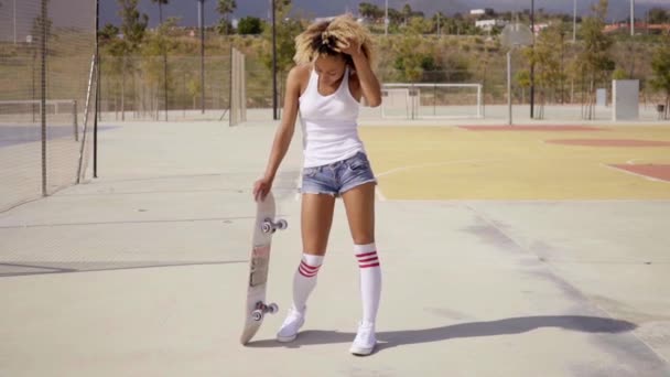 Mulher de pé com skate na quadra de basquete — Vídeo de Stock