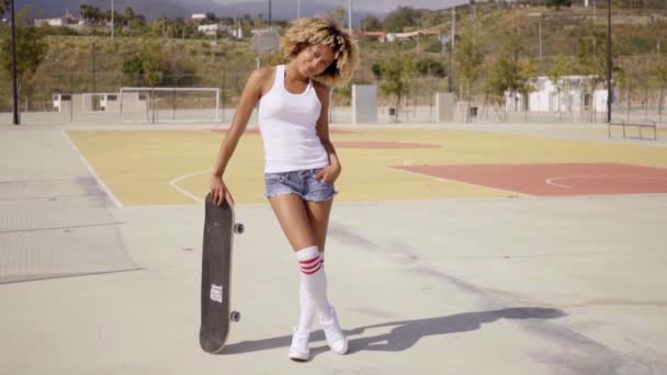 Mujer de pie con monopatín en la cancha de baloncesto — Vídeos de Stock