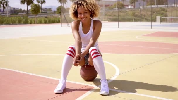 Mulher sentada em uma bola de basquete na quadra — Vídeo de Stock