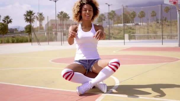 Woman sitting on a basketball ball at court — Stock Video