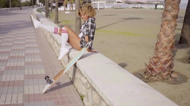 Femme assise sur parapet urbain avec longboard — Video