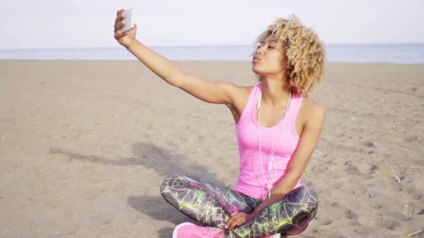 Mujer sentada en la arena y tomando selfie — Vídeo de stock