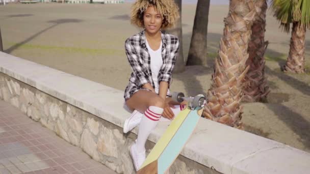 Femme assise sur parapet urbain avec longboard — Video