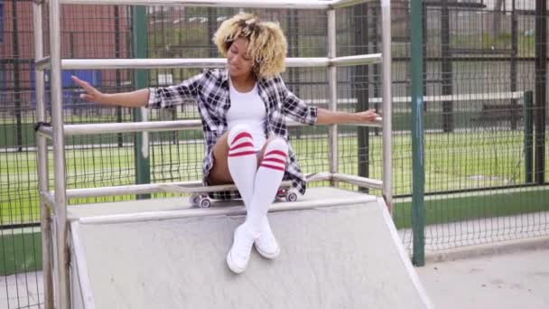 Femme assise sur skateboard au skate park — Video