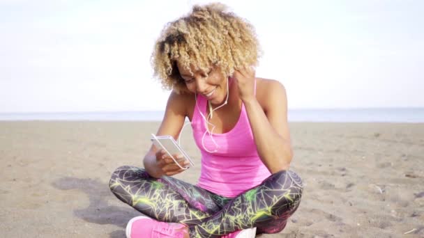 Woman sitting on sand and listening music — Stock Video