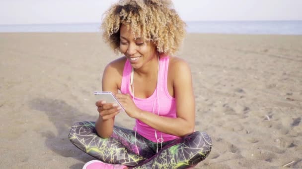 Kvinna sitter på sand och med telefonen — Stockvideo