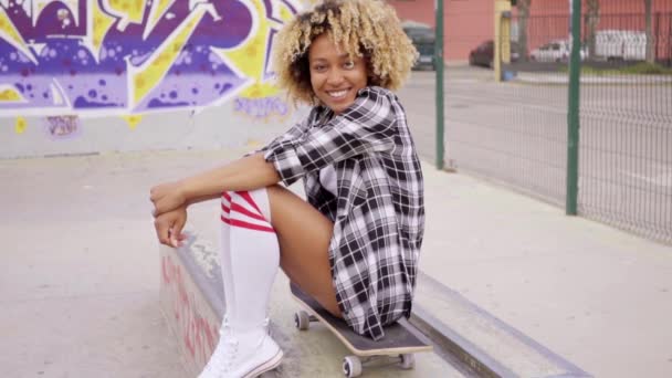 Woman sitting on skateboard at skate park — Stock Video