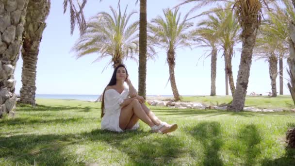 Женщина, сидящая на траве и мечтающая — стоковое видео