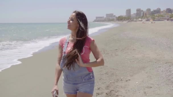 Vrouw lopen op het strand op een zonnige dag — Stockvideo