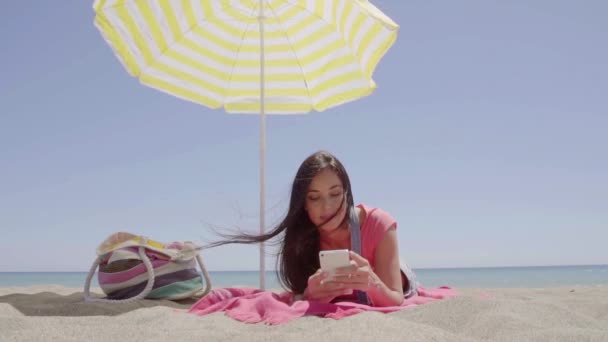 Mujer acostada en la playa bajo el paraguas — Vídeos de Stock