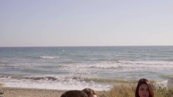 Adolescentes sentados en la playa y hablando — Vídeo de stock