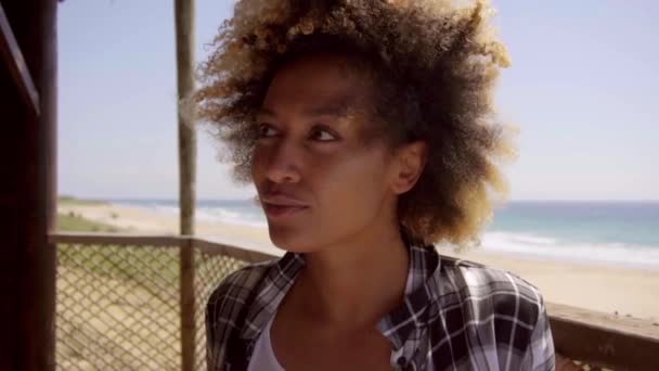 Жінка сидить на стільці проти пляжу — стокове відео