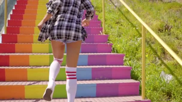 Mujer divirtiéndose en escaleras coloridas — Vídeo de stock