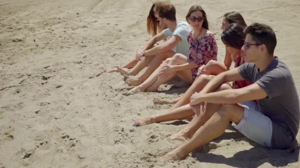 Mensen zitten op zand en praten met elkaar — Stockvideo