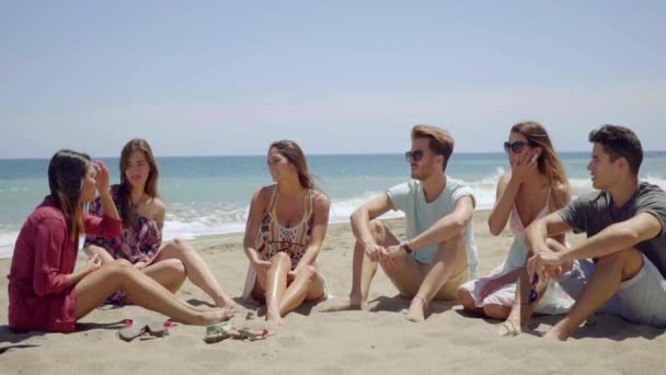 Lidé sedí na písku a rozhovory s ostatními — Stock video