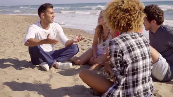 Друзья сидят на песке и разговаривают друг с другом — стоковое видео