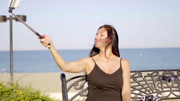 Kobieta, biorąc selfie i siedząc na ławce — Wideo stockowe