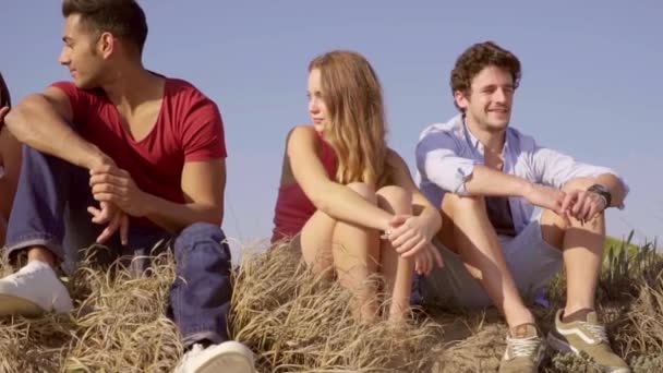 Підлітки сидять на траві і розмовляють — стокове відео