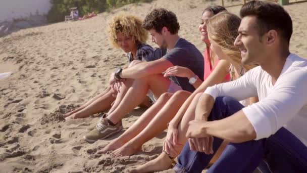 Przyjaciele siedząc na piasku i rozmawiać ze sobą — Wideo stockowe