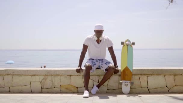 Korkuluk longboard ile oturan adam — Stok video