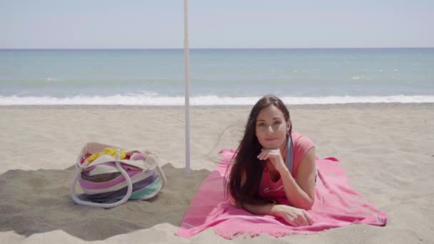 Woman laying down on beach blanket — ストック動画