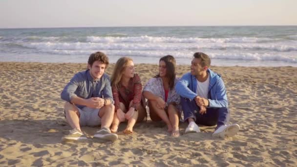 Люди сидят на песчаном пляже — стоковое видео