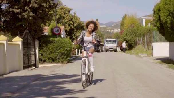 Женщина на велосипеде вниз по деревенской улице — стоковое видео