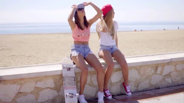 Amigos sentados en la playa con gorras de béisbol — Vídeo de stock