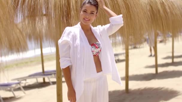Opgewonden jonge vrouw in de buurt van Palapa parasols op het strand — Stockvideo