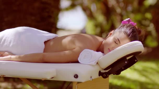 Спляча жінка лежить обличчям вниз на масажній лавці — стокове відео