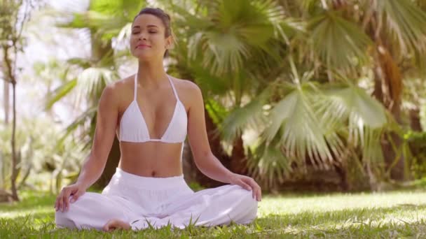 Молодая женщина медитирует в тропическом саду — стоковое видео